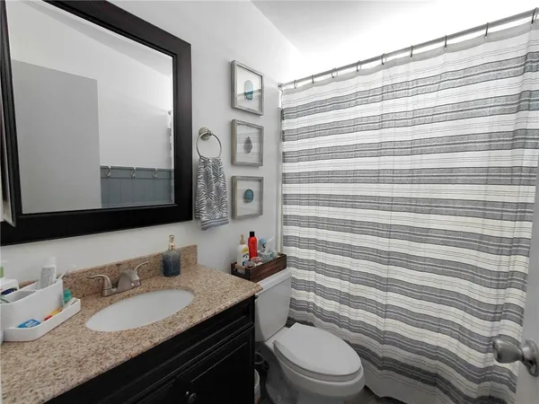 a bathroom with a granite countertop sink mirror vanity and toilet