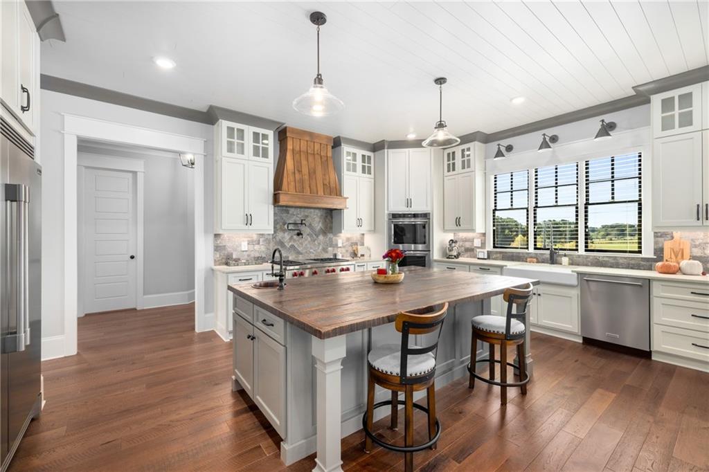 938 Austin Road Winder, GA 30680 - Photo 15 of 50 a kitchen with sink stove and white cabinets with wooden floor