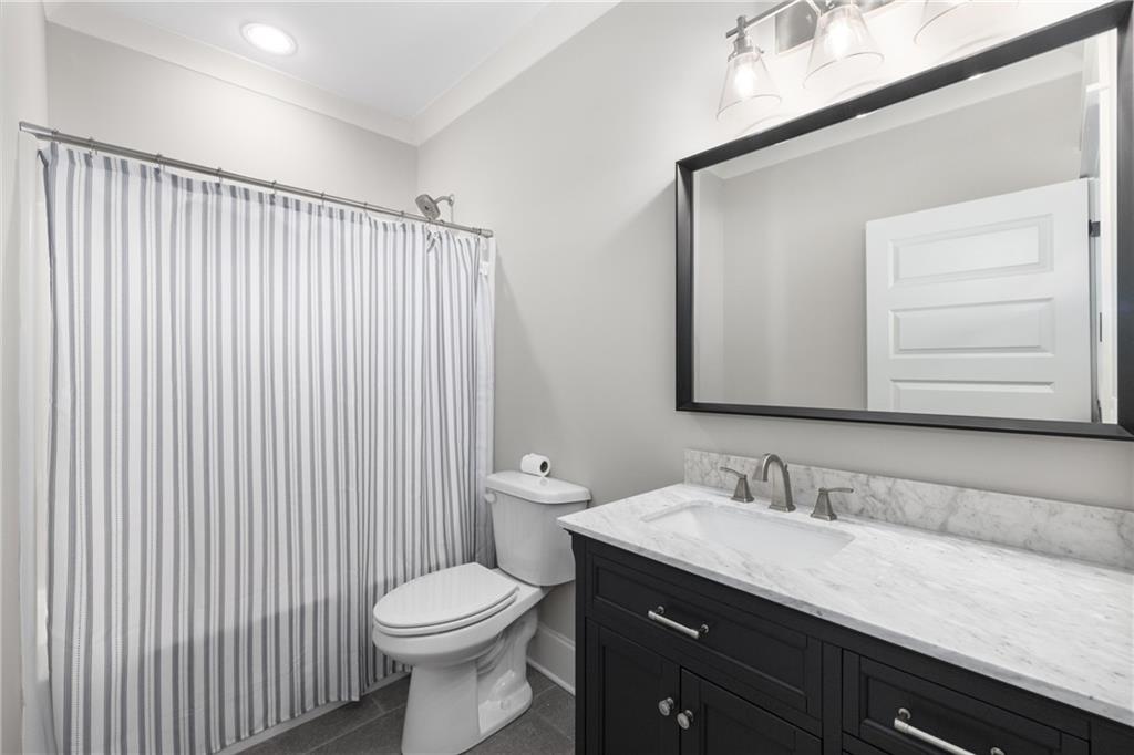 938 Austin Road Winder, GA 30680 - Photo 37 of 50 a bathroom with a granite countertop toilet a sink a mirror and a shower