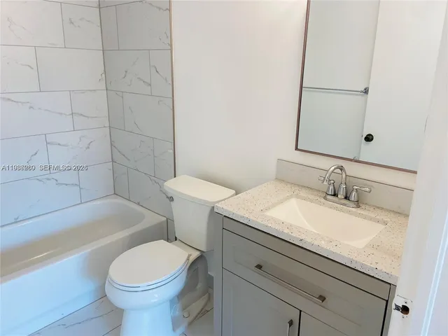 a bathroom with a granite countertop toilet sink and mirror