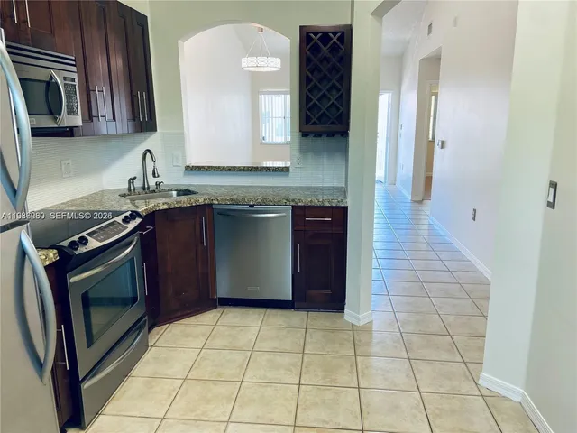 a kitchen with stainless steel appliances granite countertop a stove a sink and a microwave