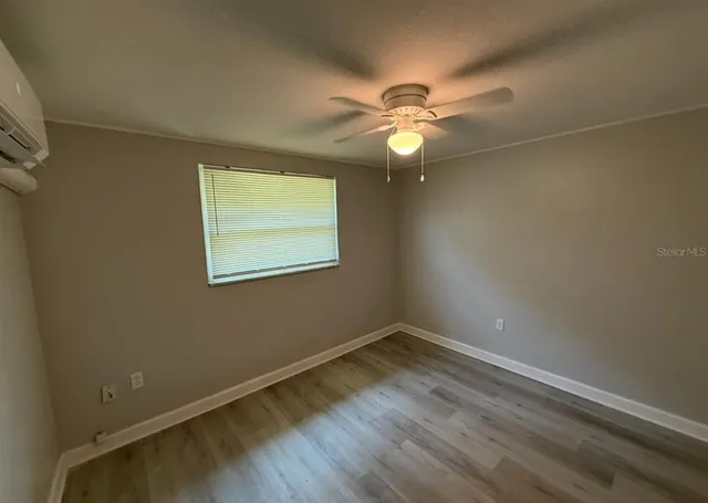 an empty room with a window and ceiling fan