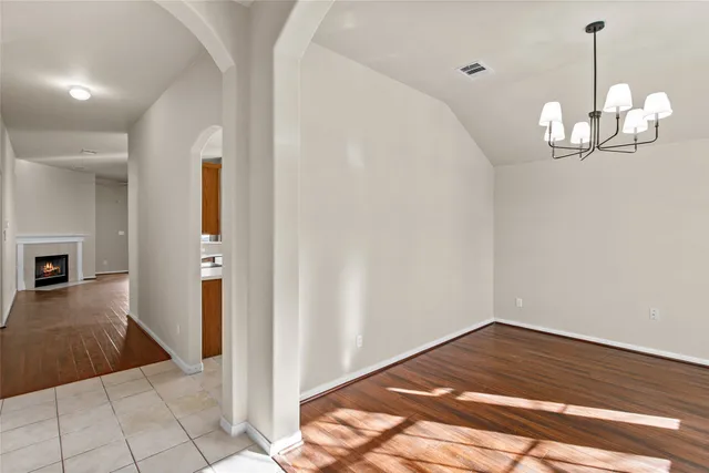 a view of empty room with wooden floor chandelier and window