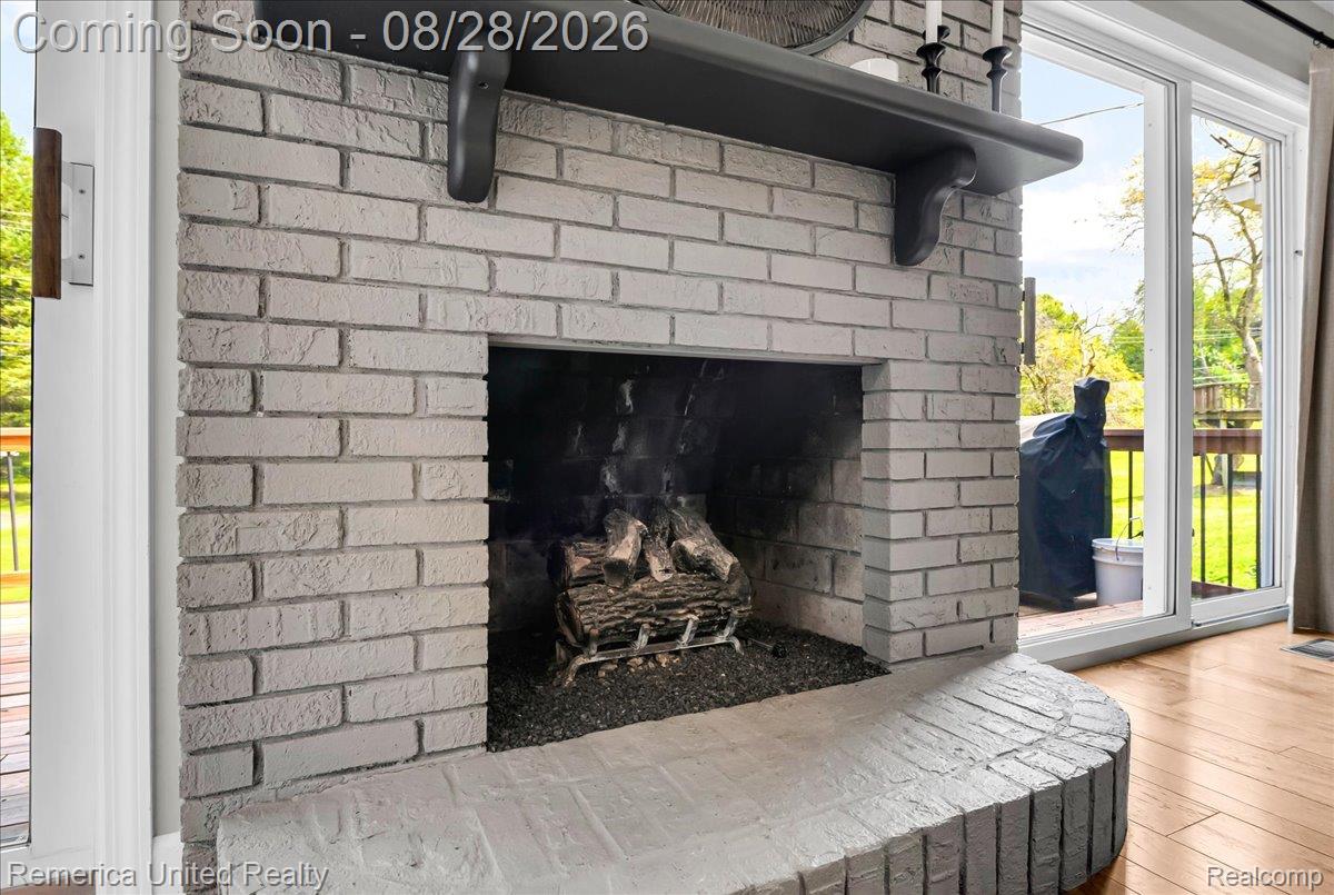 3687 Van Amberg Road Brighton, MI 48114 - Photo 6 of 56 Brick fireplace with a dark mantel, featuring a hearth with a curved edge