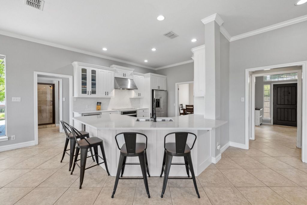 10800 Beach Road Leander, TX 78641 - Photo 6 of 39 A pristine culinary space boasts a large kitchen island, gleaming countertops, and recessed lighting.