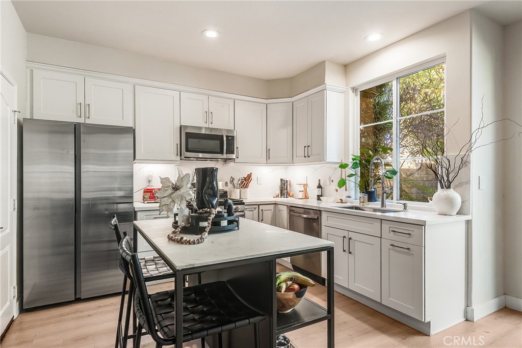 23301 Montecito Place Valencia, CA 91354 - Photo 11 of 41 a kitchen with a refrigerator a stove a sink and white cabinets with wooden floor