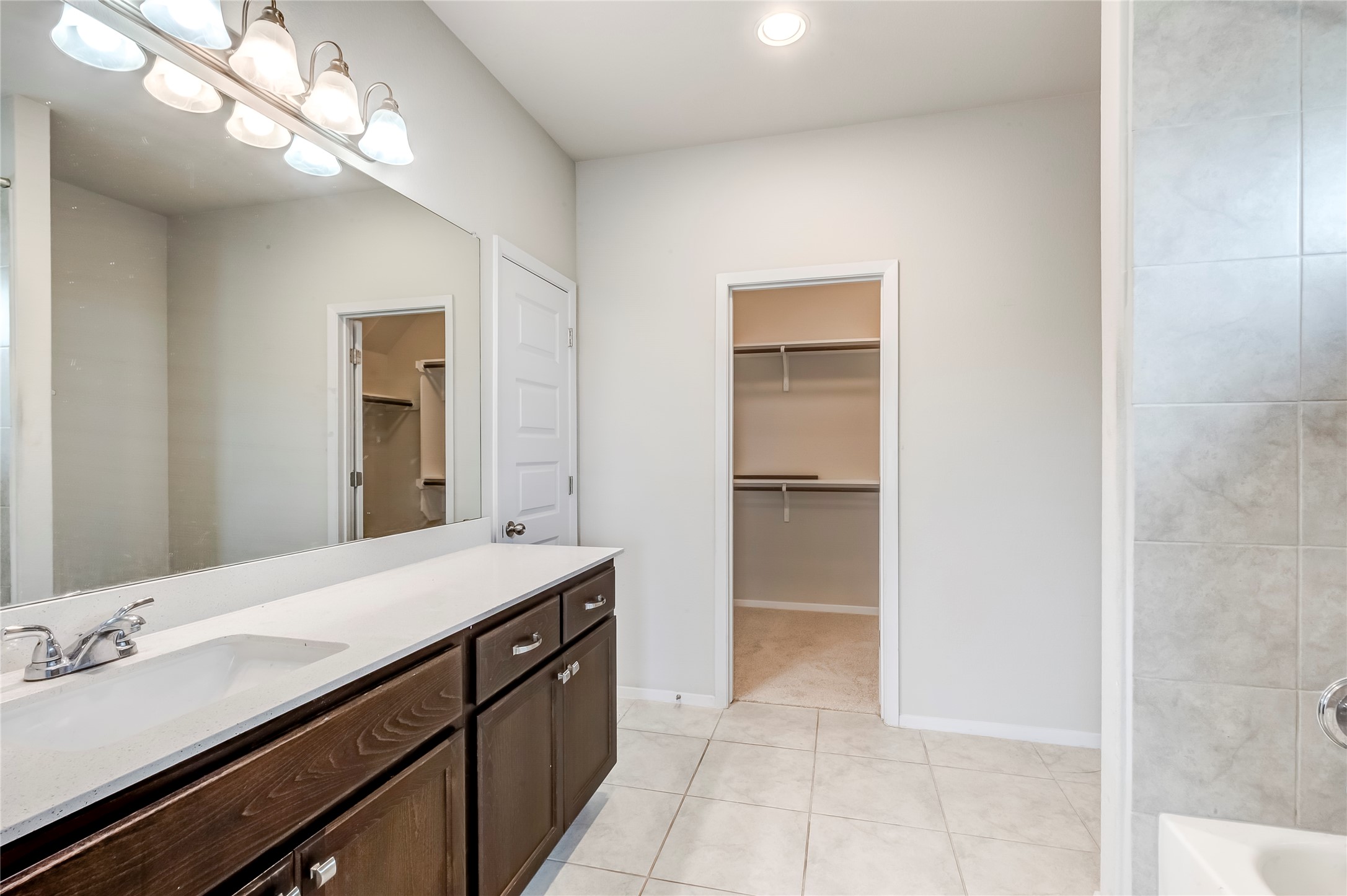 2721 Winding Creek Road Kyle, TX 78640 - Photo 18 of 27 Bathroom vanity featuring a double sink with a single faucet, an expansive mirror, and a five-light fixture