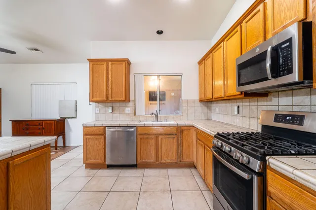 a kitchen with stainless steel appliances granite countertop a stove a sink and a microwave