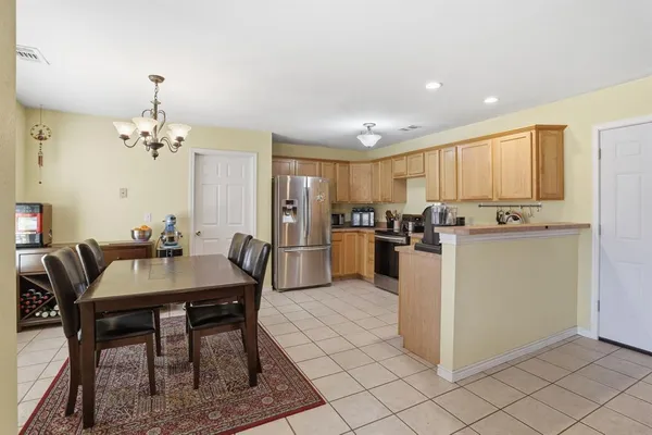 a kitchen with stainless steel appliances granite countertop a dining table chairs a refrigerator a stove a microwave oven with a dining table and chairs