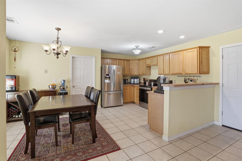 921 Calder Street Howe, TX 75459 - Photo 8 of 25 a kitchen with stainless steel appliances granite countertop a dining table chairs a refrigerator a stove a microwave oven with a dining table and chairs