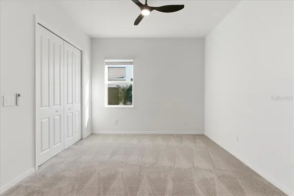 an empty room with a ceiling fan and windows