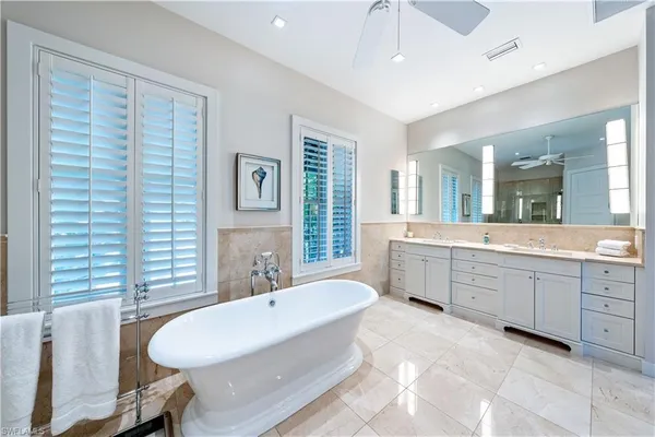 a spacious bathroom with a double vanity sink a bathtub a mirror and a shower