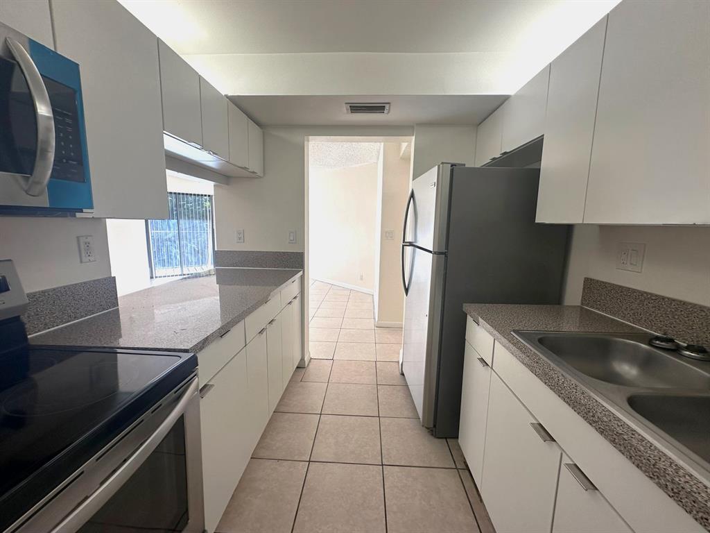 1850 North Congress Avenue, Unit 208 West Palm Beach, FL 33401 - Photo 2 of 15 a kitchen with a refrigerator and a sink