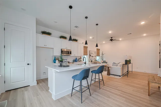 a kitchen with stainless steel appliances kitchen island granite countertop a stove a sink a dining table and chairs with wooden floor