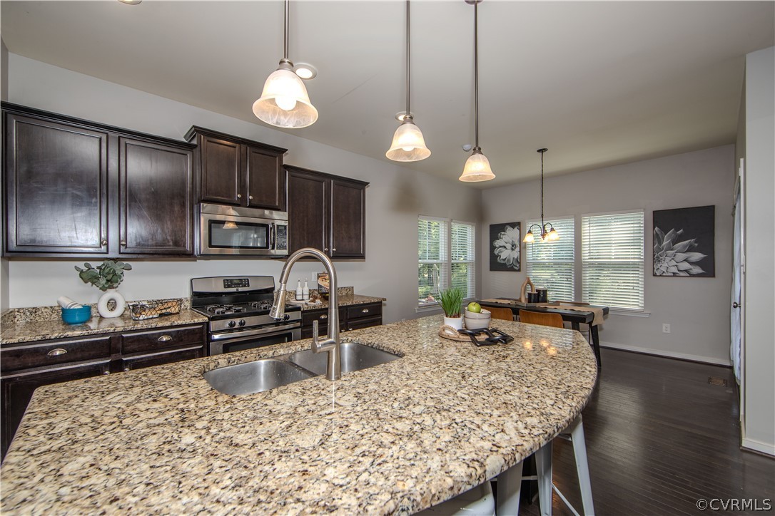 7649 Nicklaus Circle Moseley, VA 23120 - Photo 9 of 36 a kitchen with stainless steel appliances granite countertop a stove refrigerator a sink a dining table and chairs with wooden floor