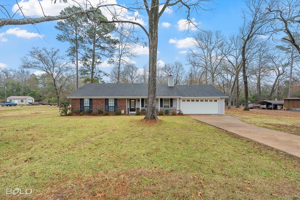 10814 Ferry Lake Road Oil City, LA 71061 - Photo 3 of 39 View of front of property with concrete driveway, a front yard, a chimney, and a garage