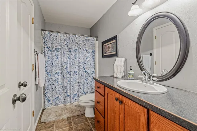 a bathroom with a granite countertop sink a toilet and a mirror