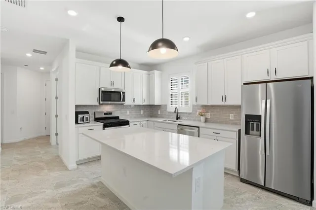 a kitchen with stainless steel appliances a stove a sink a refrigerator a center island and cabinets