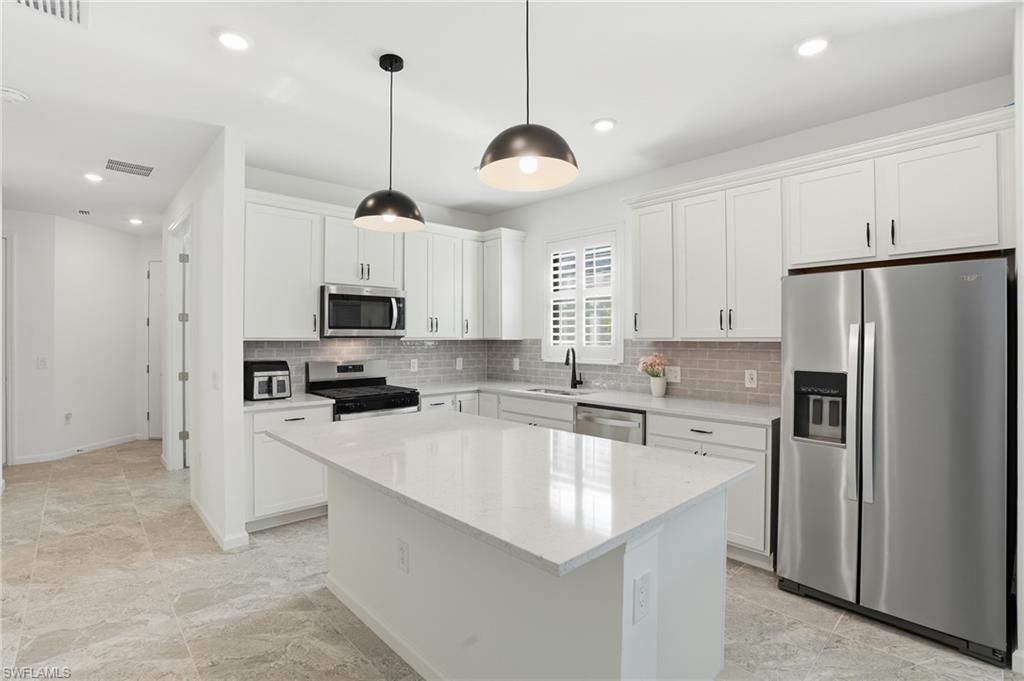 1645 Serena Avenue Naples, FL 34120 - Photo 9 of 43 a kitchen with stainless steel appliances a stove a sink a refrigerator a center island and cabinets