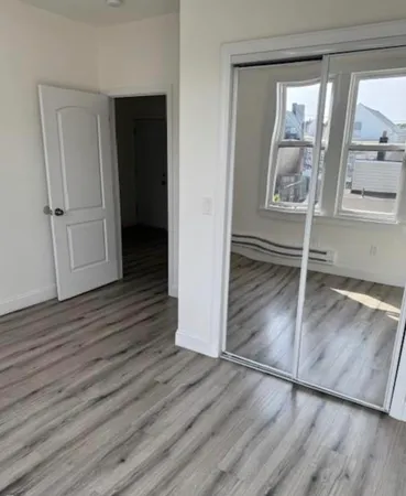 a view of an empty room with wooden floor and window