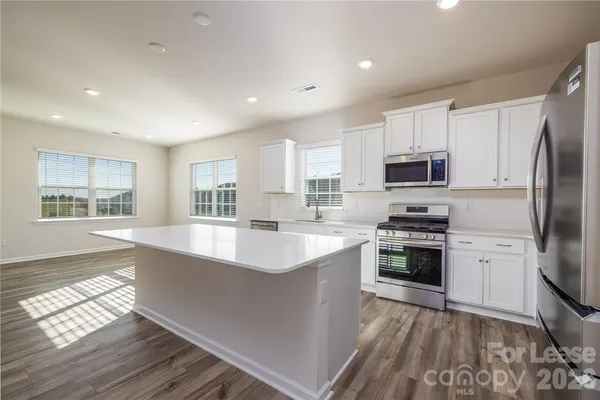 a large kitchen with stainless steel appliances granite countertop a stove a sink and a refrigerator