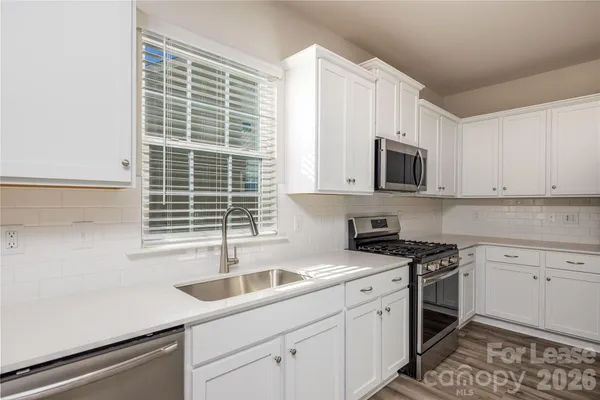 a kitchen with cabinets stainless steel appliances and a window