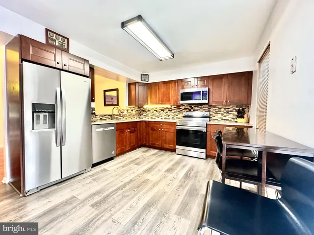 a kitchen with stainless steel appliances granite countertop a refrigerator a stove top oven a sink dishwasher and wooden cabinets