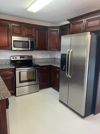 a kitchen with granite countertop a refrigerator and a stove top oven
