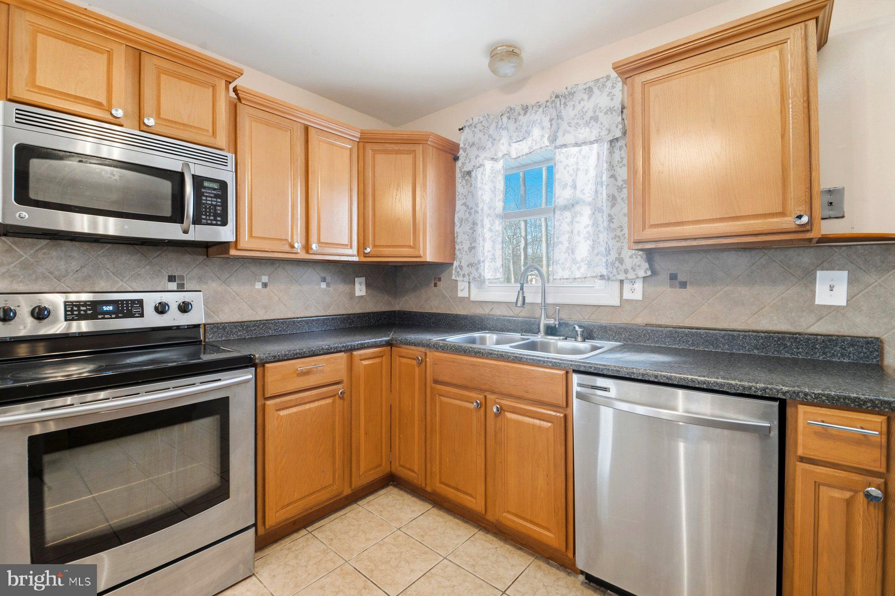 7526 Lemon Tree Court Hanover, MD 21076 - Photo 8 of 27 a kitchen with stainless steel appliances granite countertop a sink stove and microwave