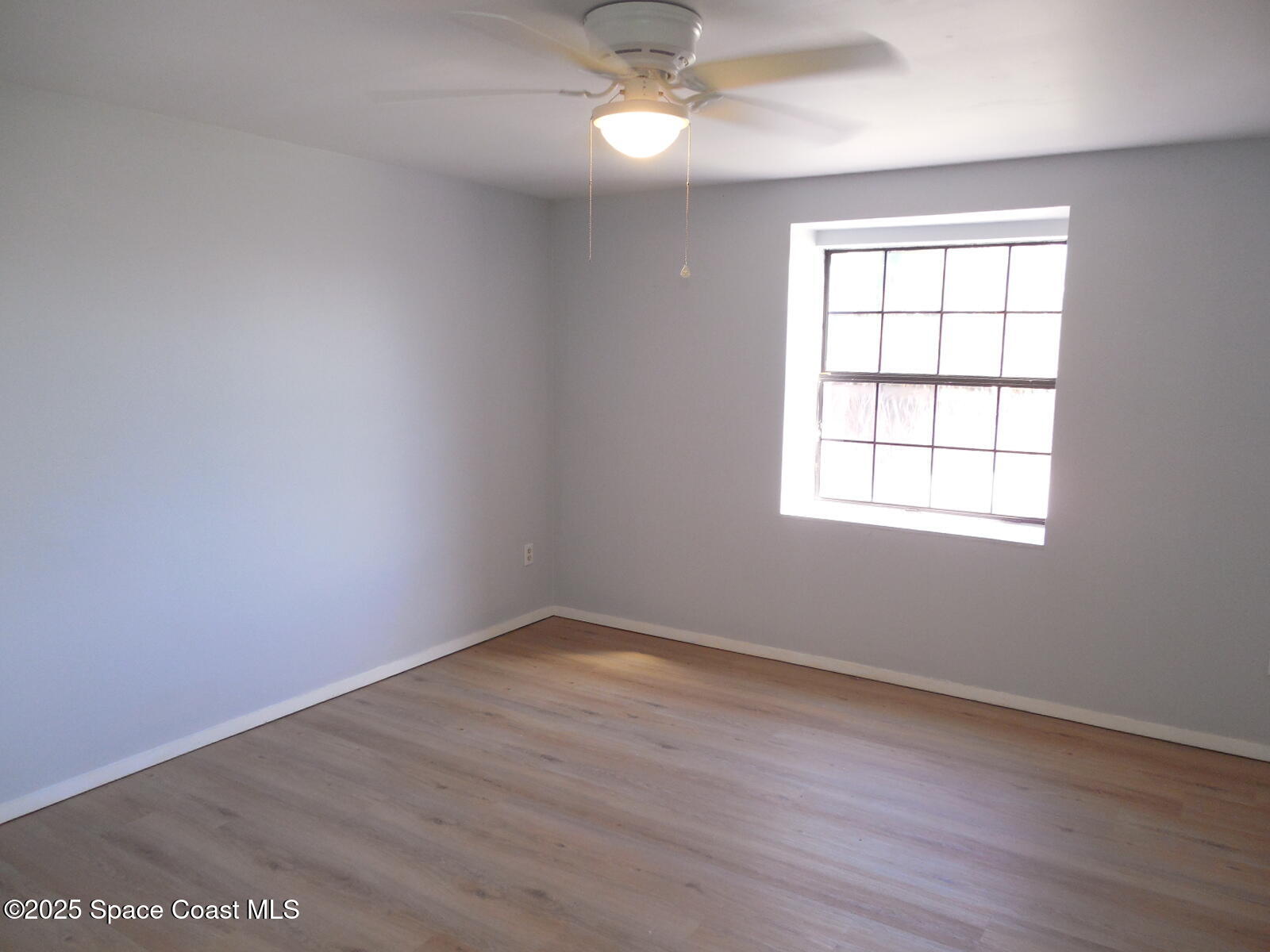 345 Ocean View Lane Indialantic, FL 32903 - Photo 19 of 31 an empty room with wooden floor windows and fan