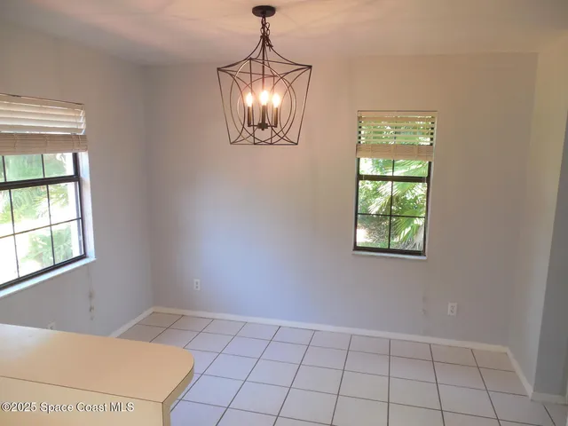 a view of an empty room with window and chandelier fan