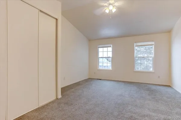 an empty room with chandelier fan and windows