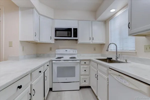 a kitchen with white cabinets and white appliances