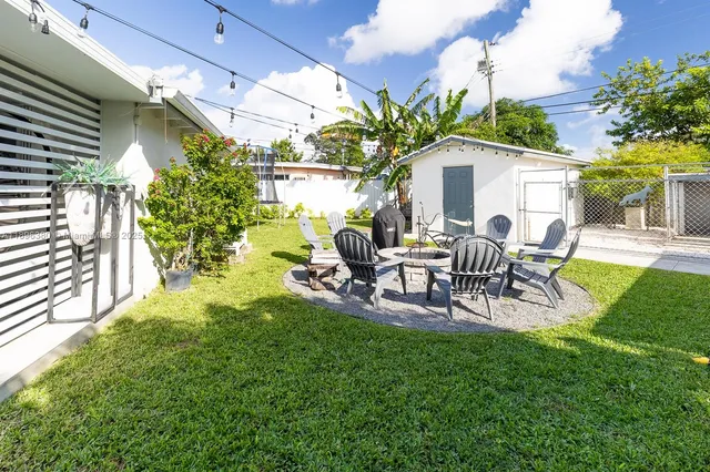 a view of a backyard with table and chairs potted plants and palm tree