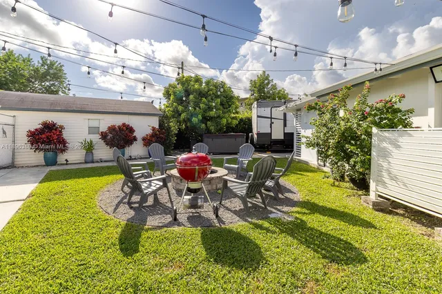 a view of a patio with table and chairs potted plants and large tree