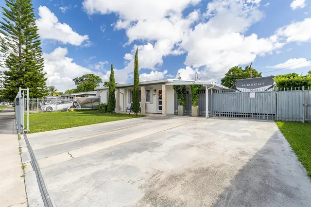 a view of a white house with a big yard and plants