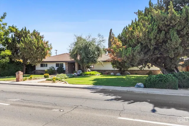 a view of a house with a yard and large trees