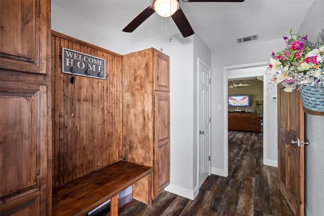a view of a hallway to a livingroom with wooden floor and windows