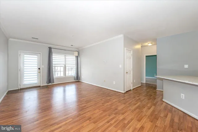 a view of an empty room with window and wooden floor