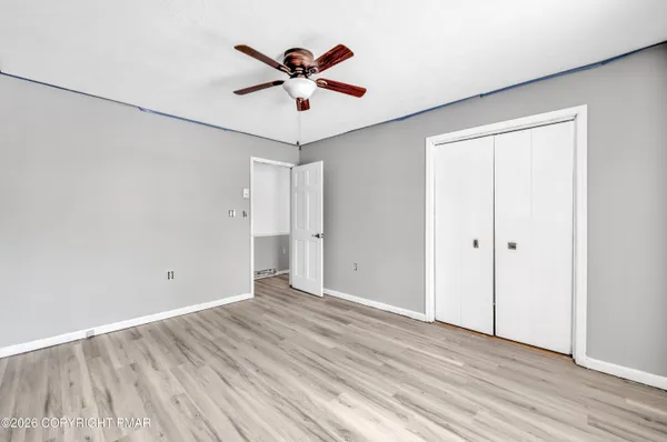 an empty room with wooden floor and ceiling fan