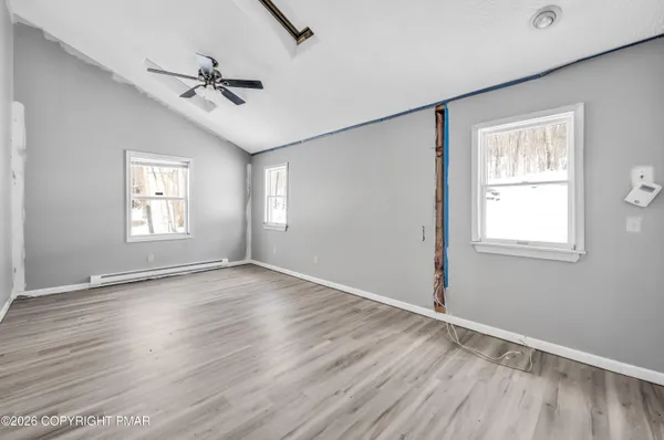 a view of an empty room with a window and wooden floor