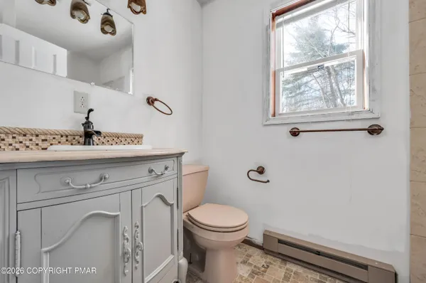 a bathroom with a toilet a sink a window and mirror