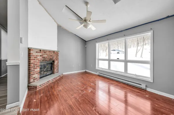 a view of an empty room with a window and hardwood floor