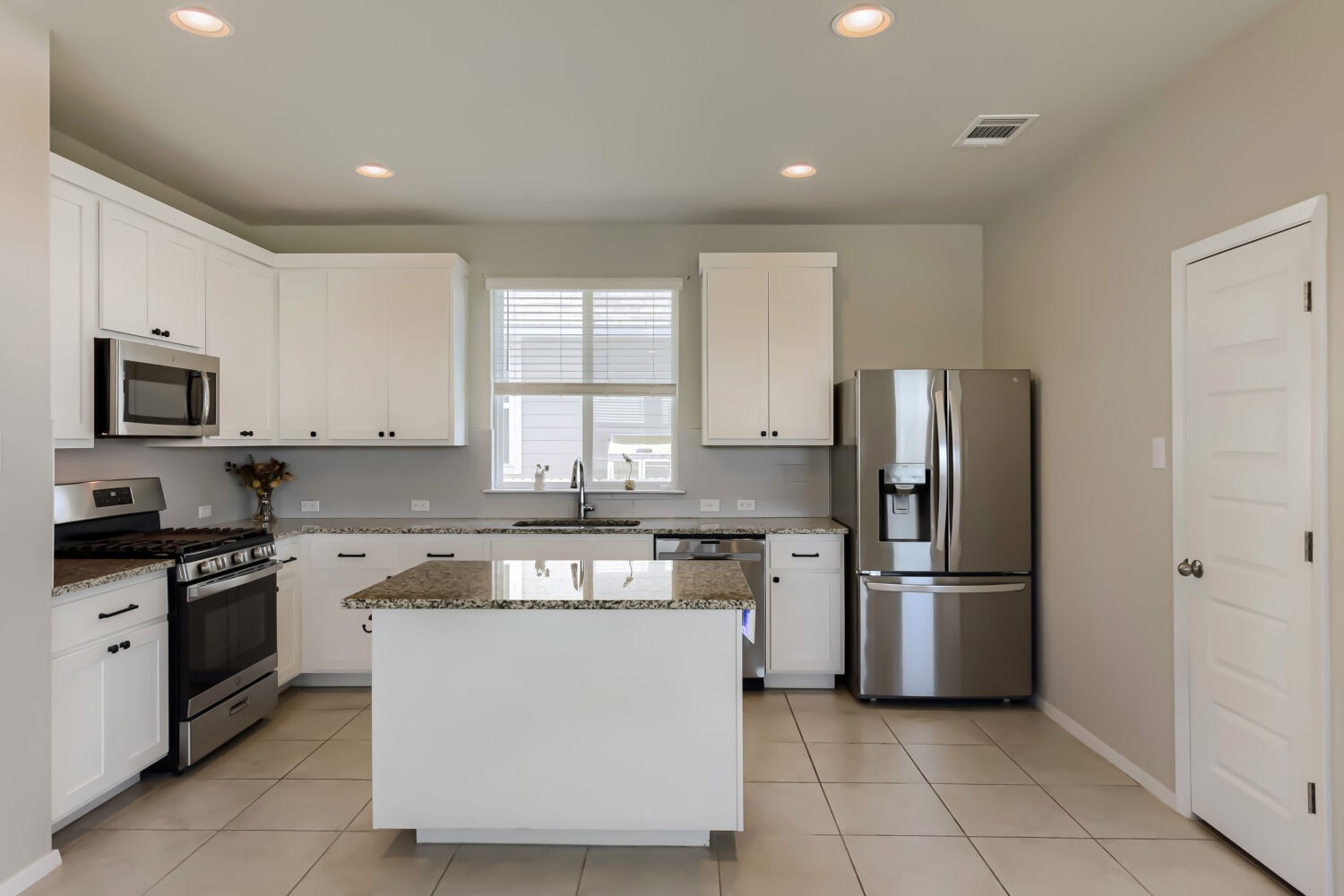 1310 Goforth Road Kyle, TX 78640 - Photo 11 of 24 Modern kitchen featuring a central island, stainless steel appliances, granite countertops, white cabinetry with dark hardware, and recessed lighting