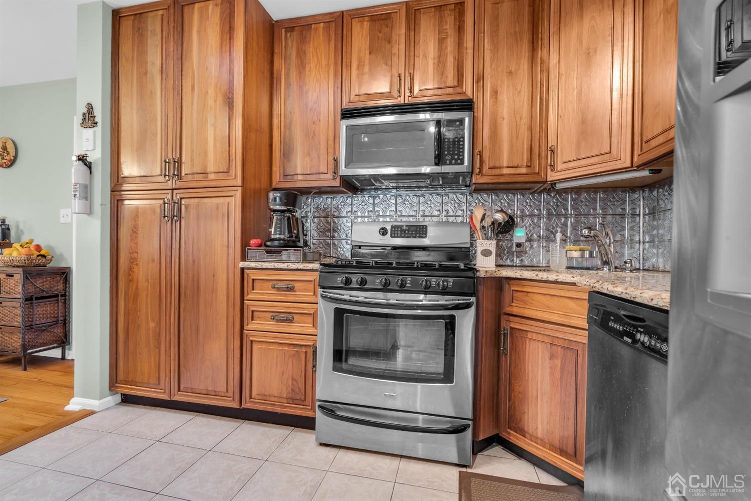 69 Stony Road Edison, NJ 08817 - Photo 13 of 33 a kitchen with granite countertop wooden cabinets stainless steel appliances and a window