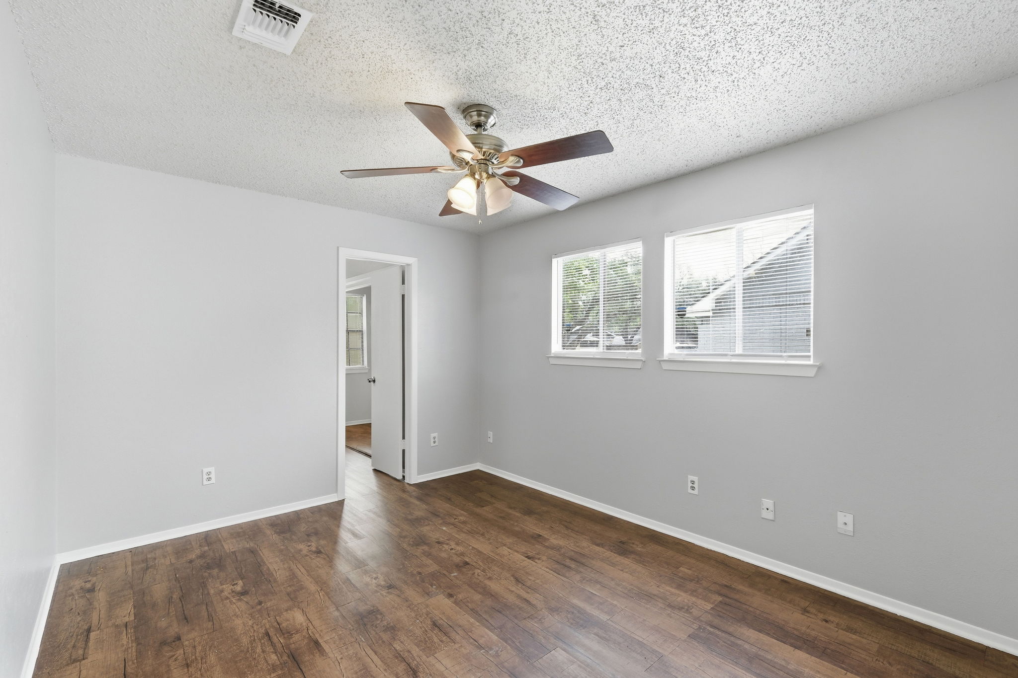 2511 Howellwood Way, Unit A Austin, TX 78748 - Photo 8 of 16 an empty room with wooden floor chandelier fan and windows