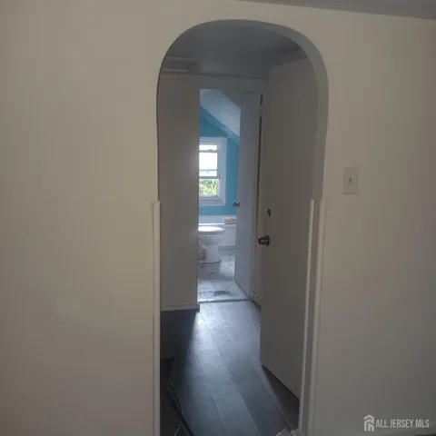 a view of a hallway with wooden floor and a bathroom