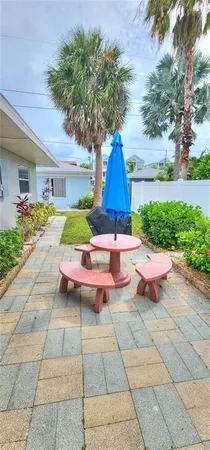a view of a backyard with table and chairs potted plants and large tree