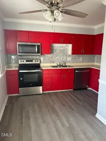 a kitchen with stainless steel appliances granite countertop a red stove cabinets and wooden floor
