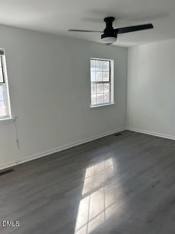 an empty room with wooden floor chandelier and windows